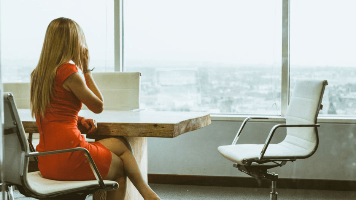 A woman sitting in a conference table looking out of a window
