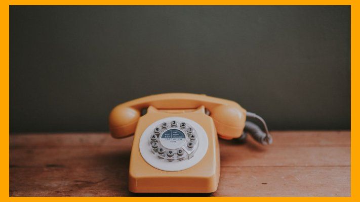 An old yellow phone on a wood table